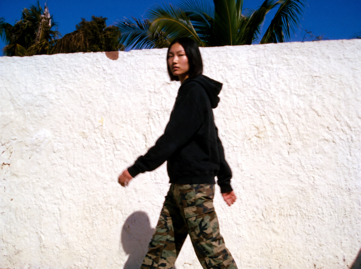 model walking past a white wall in a black hoodie