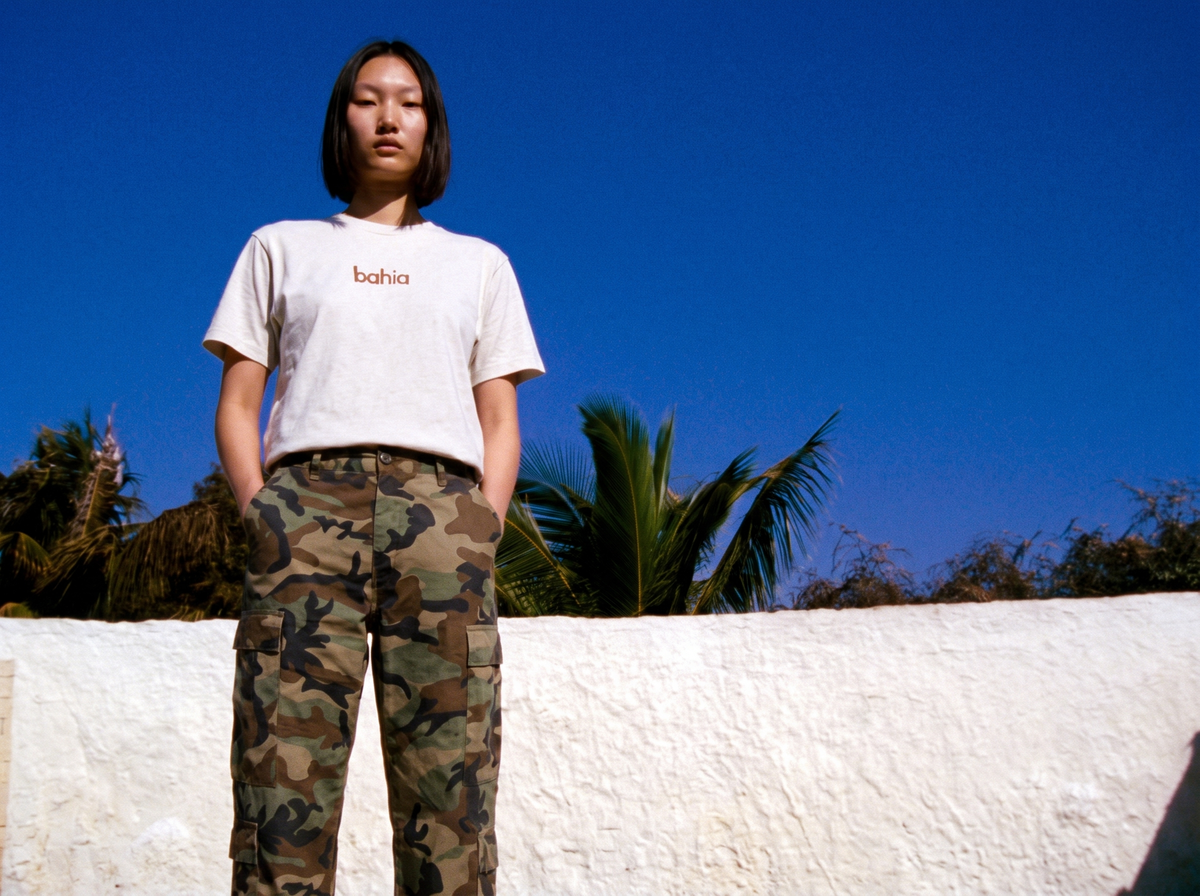 model standing in the bahia tee under a blue sky